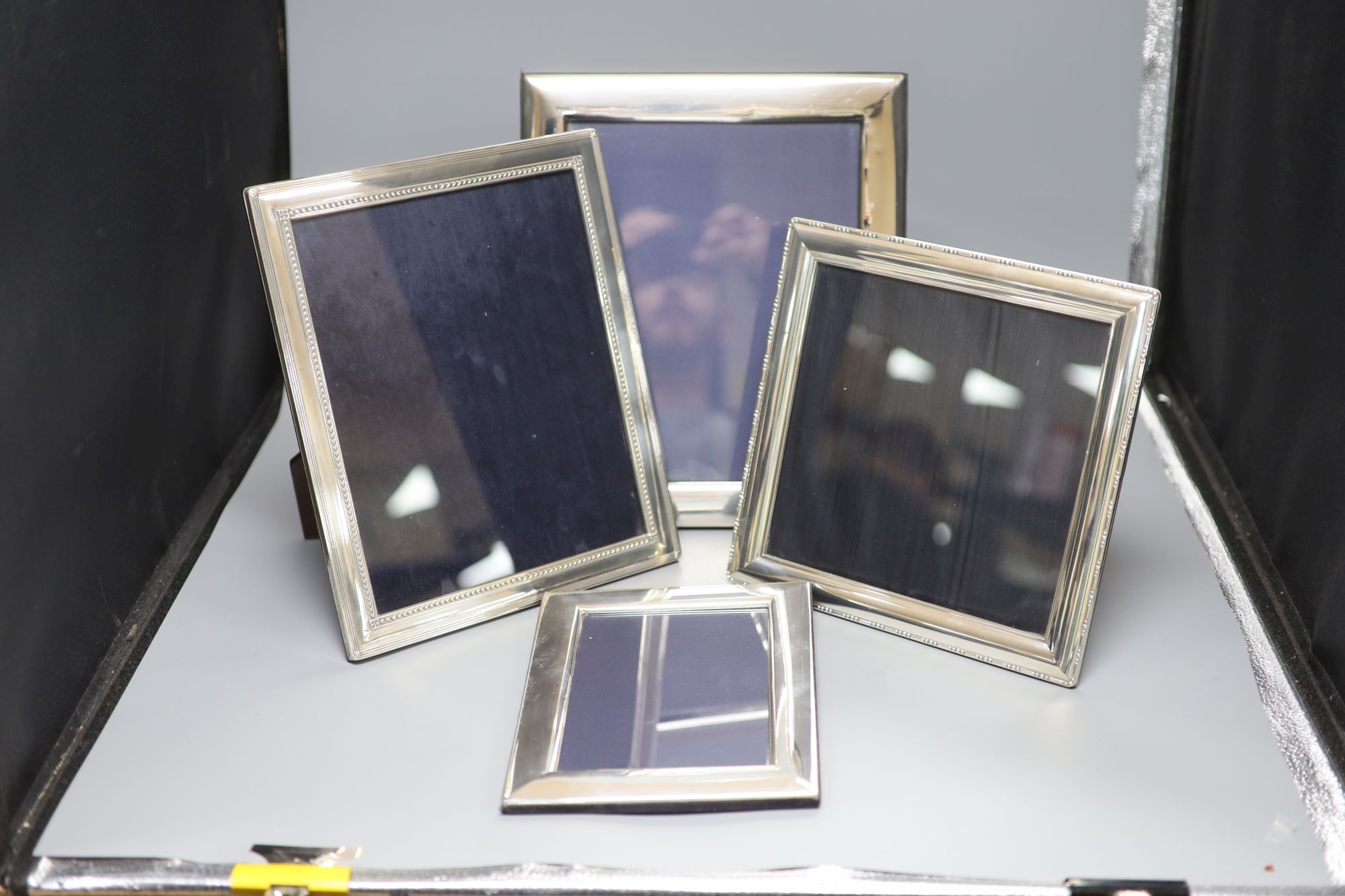 Four modern silver easel photographs frames, two with decorative banding